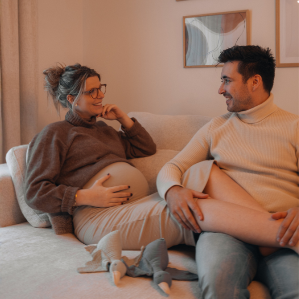 Schwangere Frau und ihr Mann gemeinsam auf dem Sofa